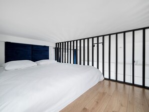 Ein modernes Schlafzimmer mit einem großen Bett, einem dunklen Kopfteil und Holzboden.