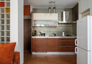 Eine moderne Küche mit Holzausstattung, einem weißen Kühlschrank und einem eingebauten Herd.