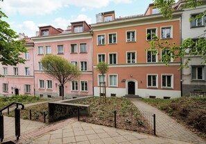 A row of multi-story residential buildings with a paved courtyard, a wooden ladder, and a metal fence. - Bednarska Royal Route Apartment (Warszawa)