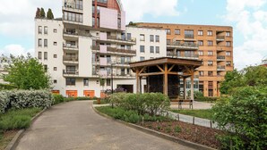A multi-story residential building with balconies, a covered outdoor seating area, and a landscaped garden. - Park Praski Homely Apartment (Warszawa)