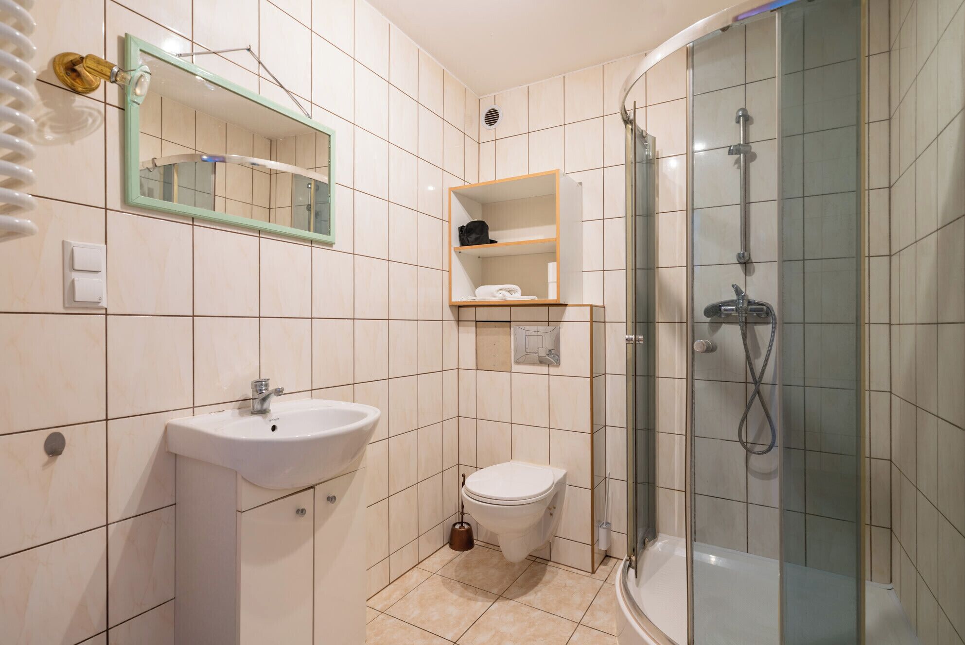 Une salle de bain équipée d’un lavabo, de toilettes, d’une douche et d’un miroir.