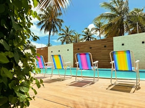 A poolside area with lounge chairs and a wooden deck.