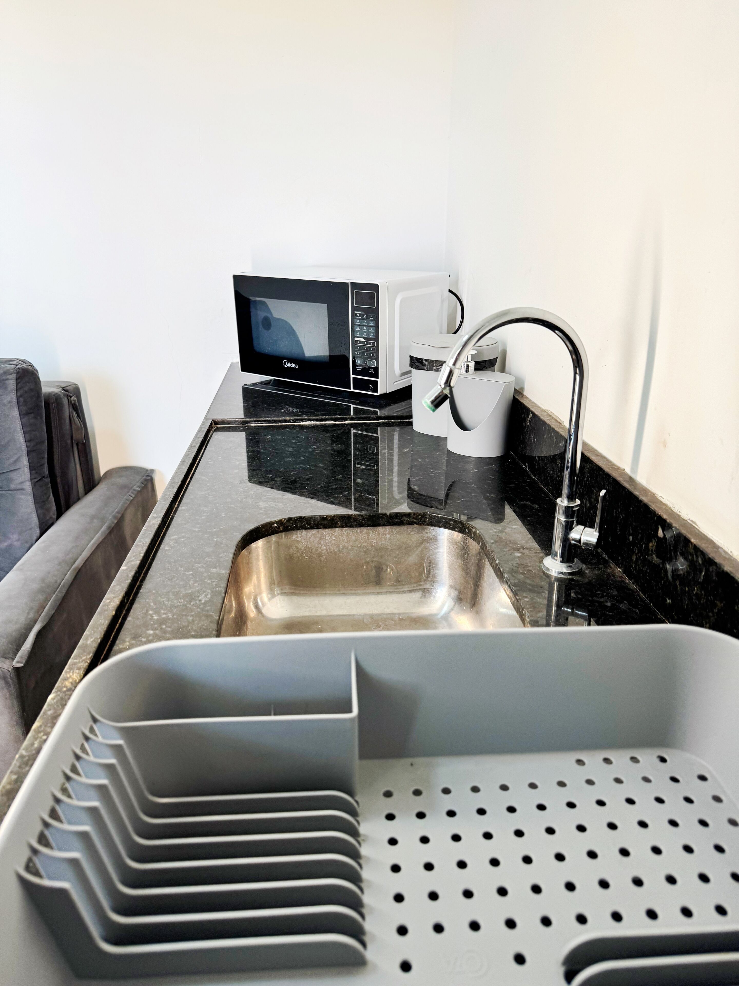 Una kitchenette compacta con microondas, un lavamanos y una cafetera.