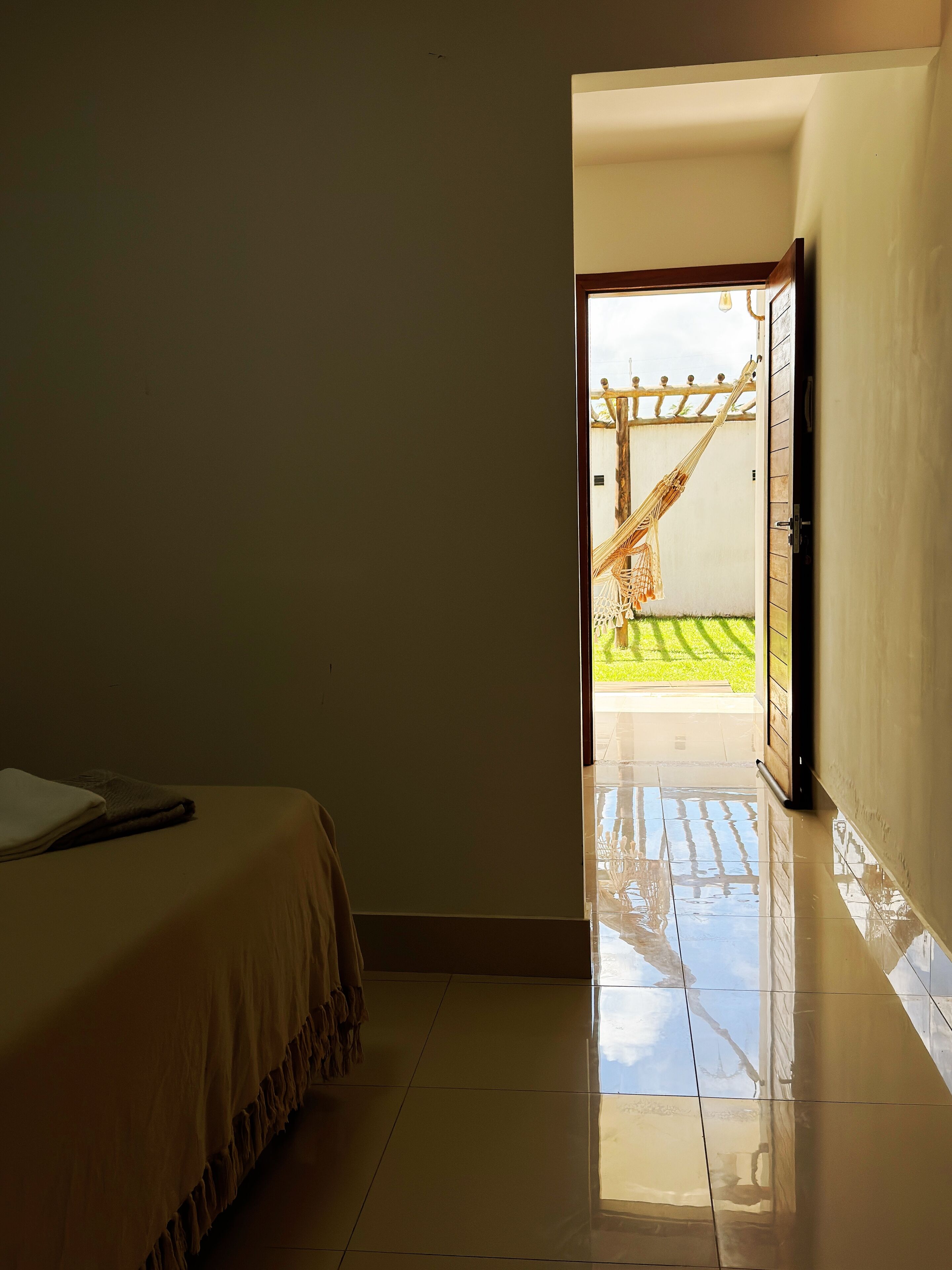 Quarto com cama, porta para o exterior e vista para uma rede lá fora.