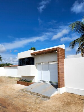 A modern building with a garage, a paved driveway, and a palm tree.