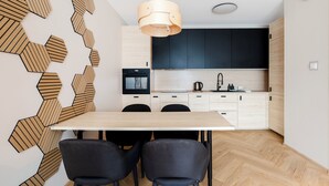 A modern kitchen with a wooden herringbone wall design, a central island, and black cabinets.