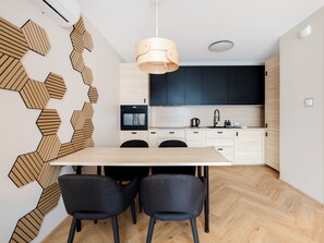 Une cuisine moderne avec un mur décoré de motifs en chevrons en bois, un îlot central et des meubles de couleur noire.