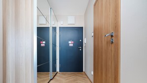 A hallway with wooden flooring, a blue door with a sign, and a wooden wardrobe.