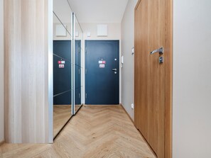 Ein Flur mit Holzboden, einer blauen Tür mit einem Schild und einem Holzschrank.