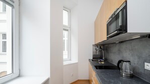 Uma cozinha compacta com micro-ondas, pia, chaleira e armários de madeira.