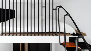 Uma cama beliche com estrutura metálica, cabeceira de madeira e colchão branco.
