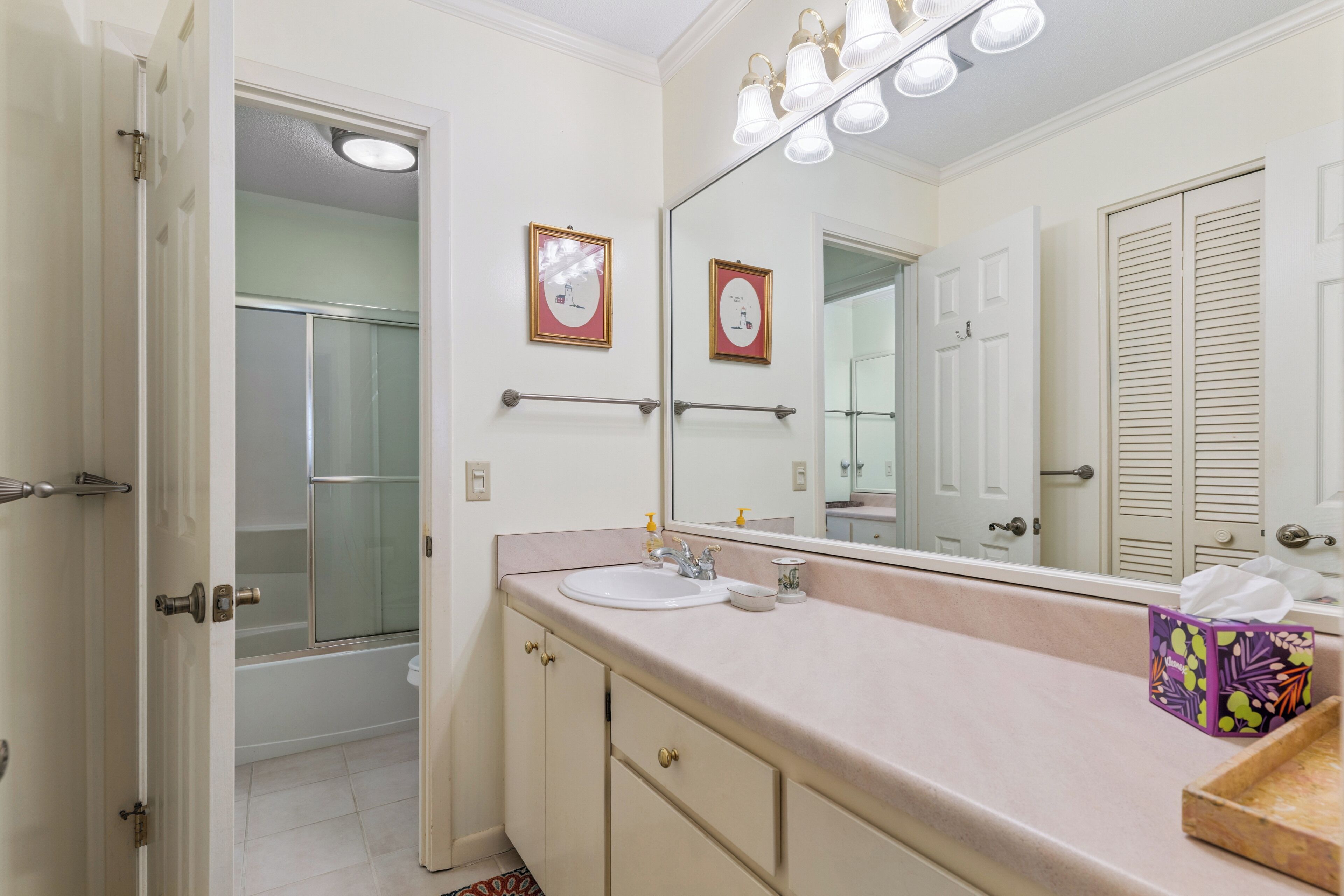 A bathroom with a sink, mirror, and towel dispenser.