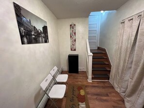 A narrow hallway with a staircase, a welcome sign, a door, and a small black speaker. - Spacious 3BR Niagara Stay + Backyard (Niagara Falls)