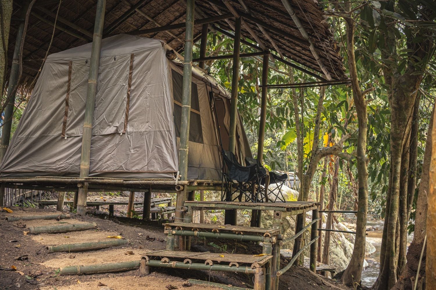 Ein rustikaler, überdachter Sitzplatz im Freien mit Holzwegen und einer Lounge-Ecke.