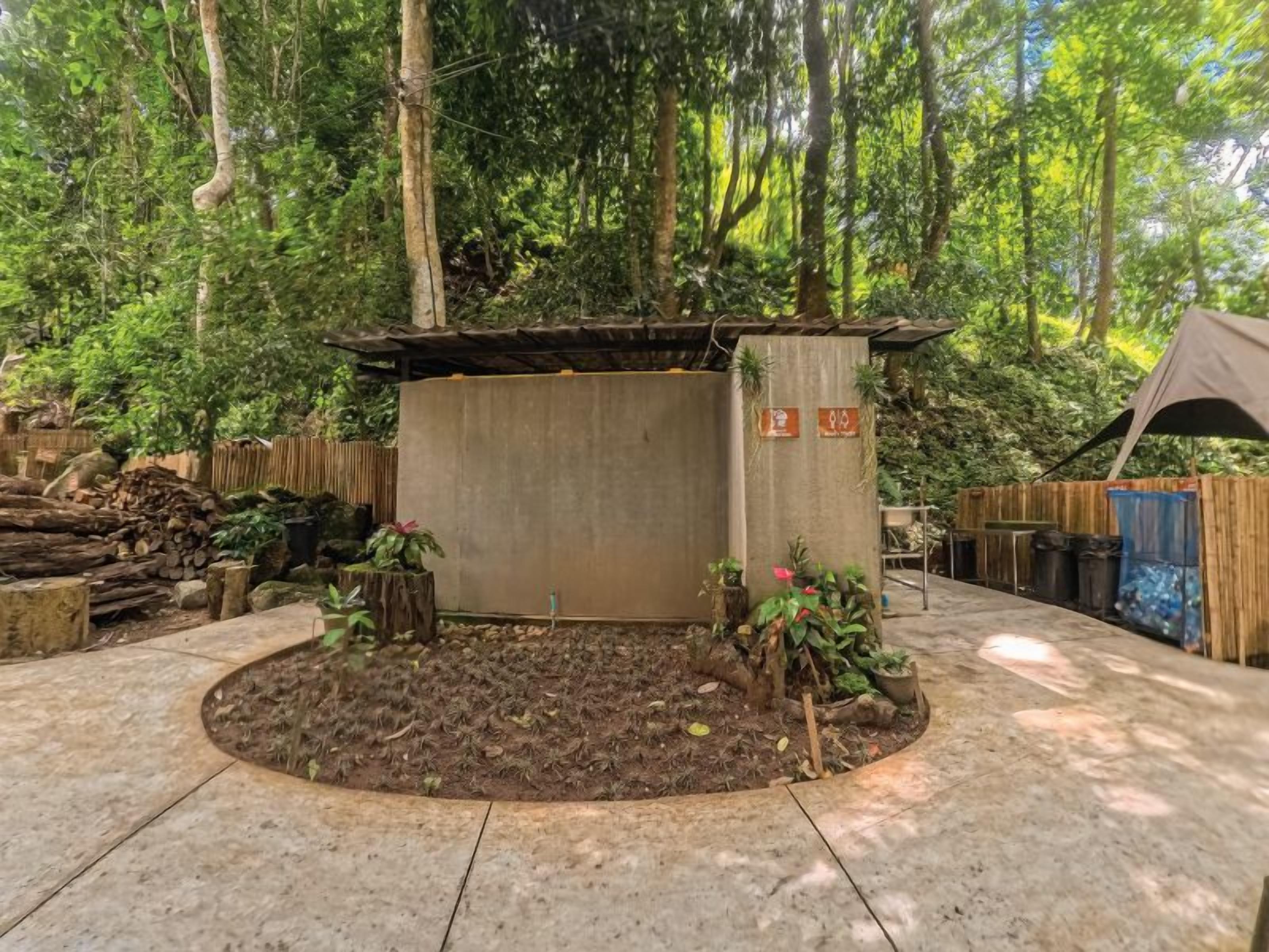 A circular garden area with a central structure, surrounded by a wooden fence and trees.