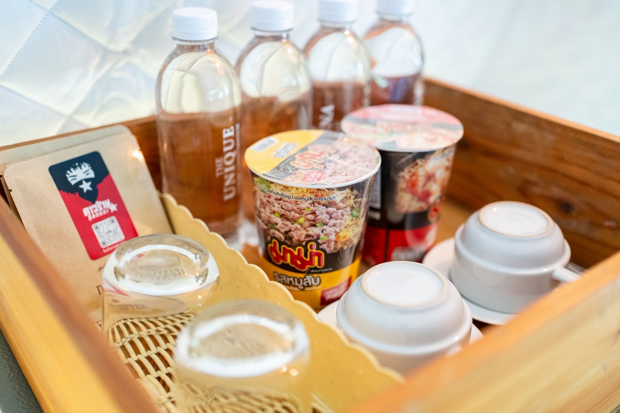A tray with various food items including a packaged snack, a can of noodles, and several bottles of beverages.