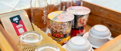 A tray with various food items including a packaged snack, a can of noodles, and several bottles of beverages.