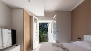 Une chambre avec un lit, une télévision, une armoire et un balcon.