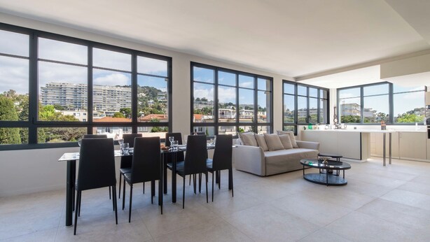 Un salon moderne avec un coin repas, de grandes fenêtres et une vue sur le paysage urbain.