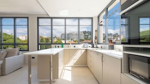 Une cuisine moderne dotée de grandes fenêtres, d’un coin repas et offrant une vue sur la ville.