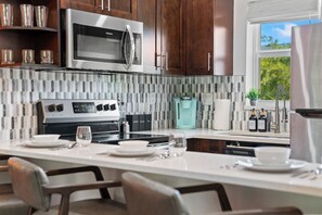 A modern kitchen with dark wooden cabinets, a stainless steel microwave, a built-in oven, and a coffee station. - Walk to Beach, Heated Pool, Hot Tub, Pets OK, Sleeps 6, Boca Raton (Boca Raton)