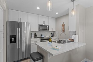 A modern kitchen with a stainless steel refrigerator, a microwave, a sink, and a countertop with a bottle of wine. - Minutes to Old Town (Scottsdale)