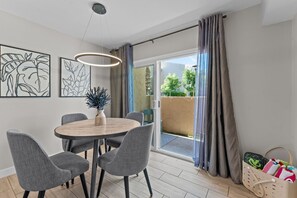 A modern dining area with a round table, grey chairs, and a hanging light fixture. - Minutes to Old Town (Scottsdale)