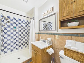 Een badkamer met douche, wastafel, toilet en spiegel.
