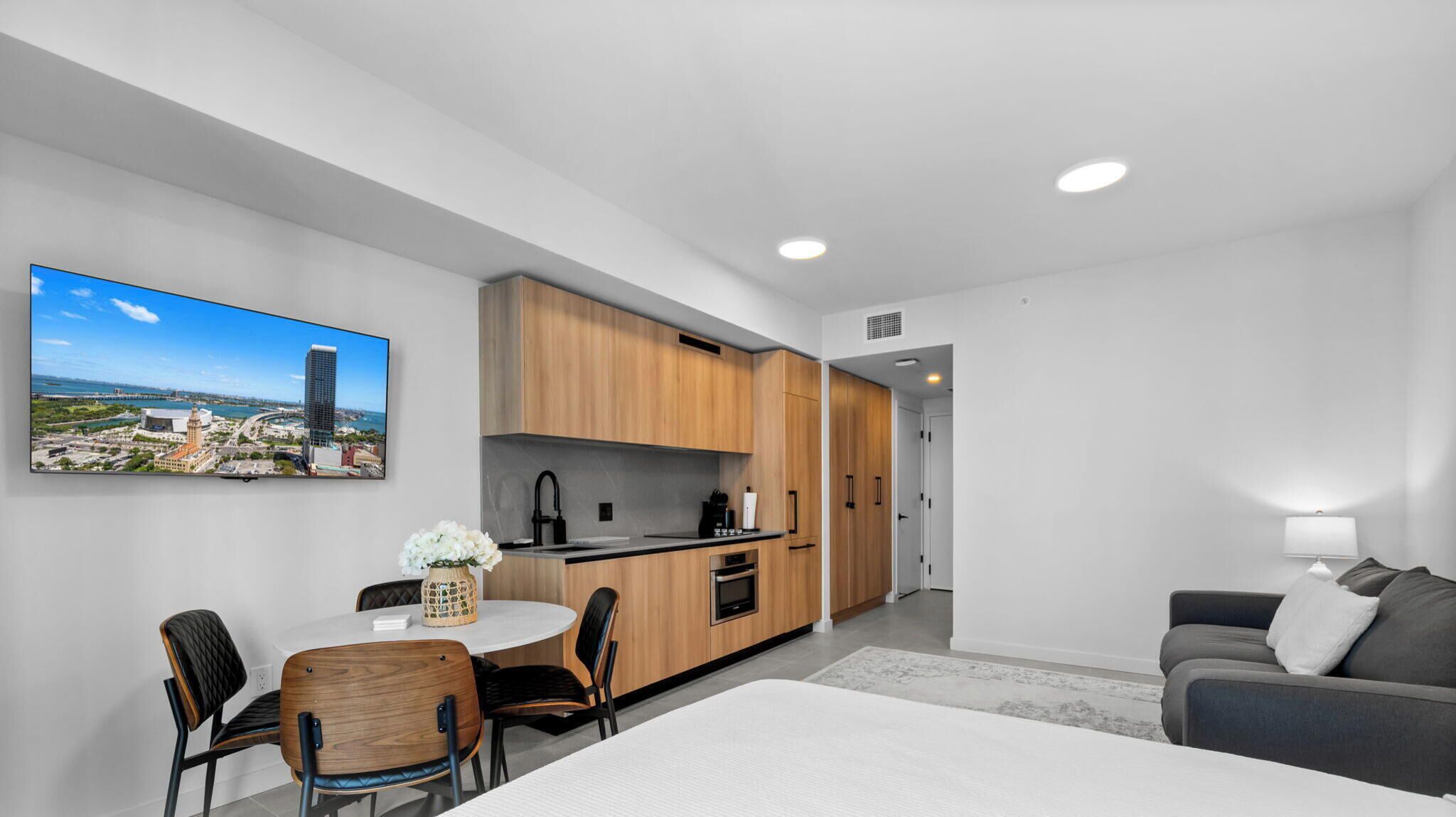 A modern apartment with a dining area, kitchenette, and a living space with a sofa and a lamp.