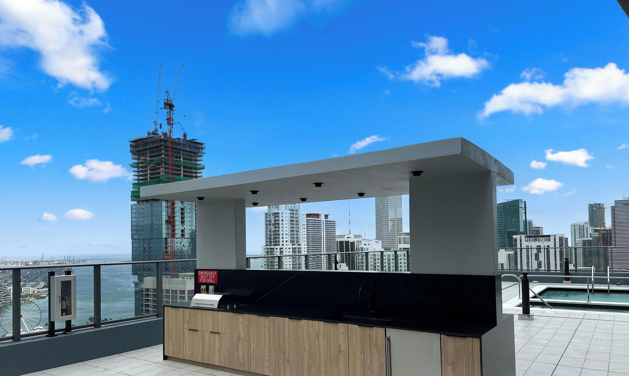 A rooftop bar with a city skyline view, a pool, and a Ferris wheel in the background.