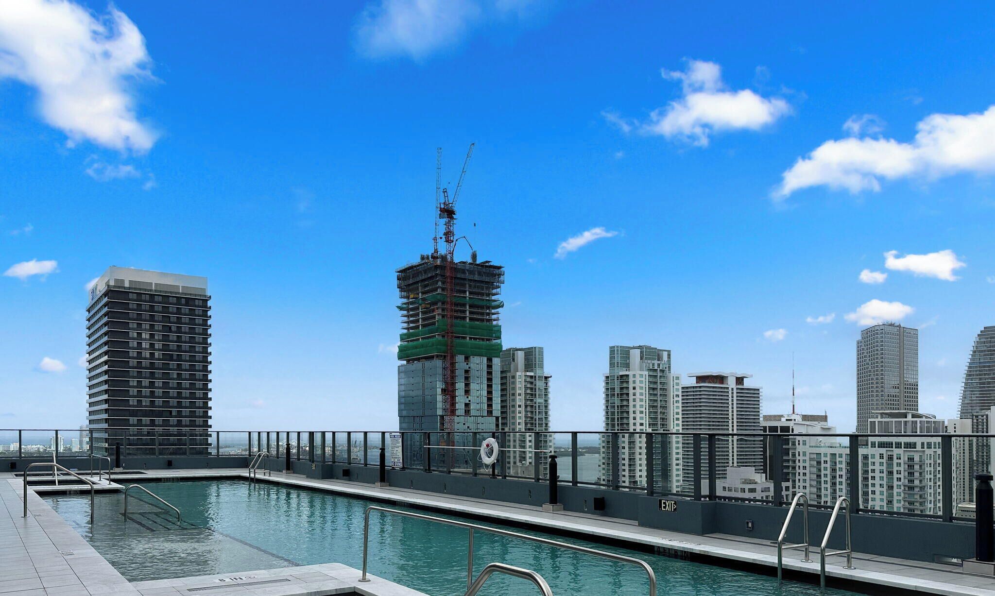 A rooftop pool with a city skyline in the background, including a construction crane.