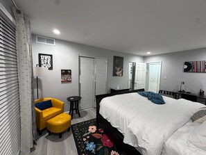 Un dormitorio con cama, una silla, un escritorio y un armario.