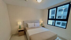 Ett hotellrum med en säng, två sängbord, ett fönster med utsikt över byggnader och en taklampa.