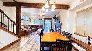 A spacious living area with a wooden dining table, leather sofa, and a ceiling fan. - The Timberline Haus - Where Pines Meet The Payette (McCall)