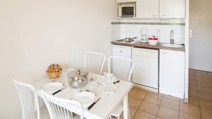 Een kleine keuken met witte kastjes, een magnetron, een koffiezetapparaat en een spoelbak.