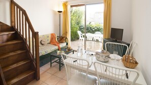 Een eetruimte met een tafel, stoelen, een televisie en een trap.