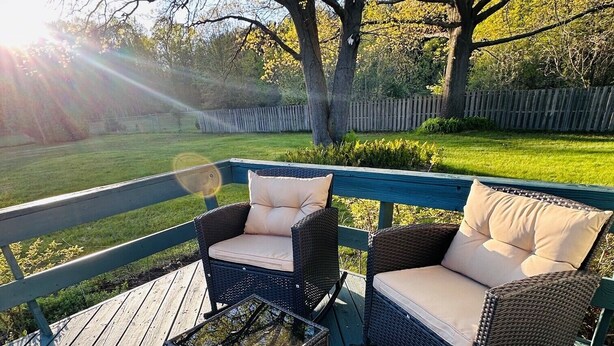 Eine Terrasse mit Korbmöbeln und einem Tisch mit Glasplatte.