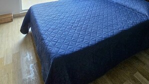 Ein Zimmer mit einem Bett, einem Nachttisch, einer Lampe und Meerblick, sowie einer Schiebetür.