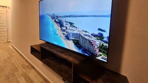 Ein Flachbildfernseher an einem Holzboden angebracht, zeigt eine Küstenstadt mit Gebäuden und einem Strand.