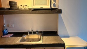 Eine kleine Küche mit einer Mikrowelle, einem Spülbecken und einem kleinen Kühlschrank.