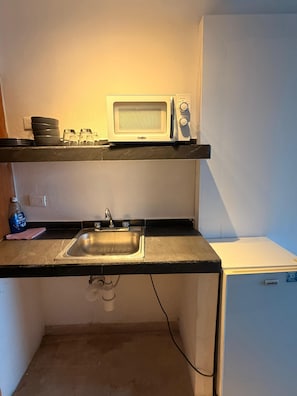 A compact kitchen with a microwave, a sink, and a small refrigerator. - LUNA Y SOL CARIBE SUITES BY CANCUN PLAZA (Cancún)