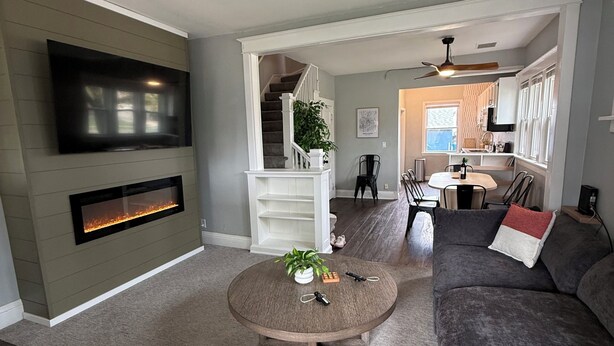 A living room with a fireplace, a flat-screen TV, a round coffee table, a sofa, and a staircase leading to a kitchen. - Superlisting! Entire Duplex, perfect for 2 families traveling together (Sioux Falls)