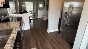 A modern kitchen with a stainless steel refrigerator, granite countertops, and a wooden floor. - Superlisting! Entire Duplex, perfect for 2 families traveling together (Sioux Falls)