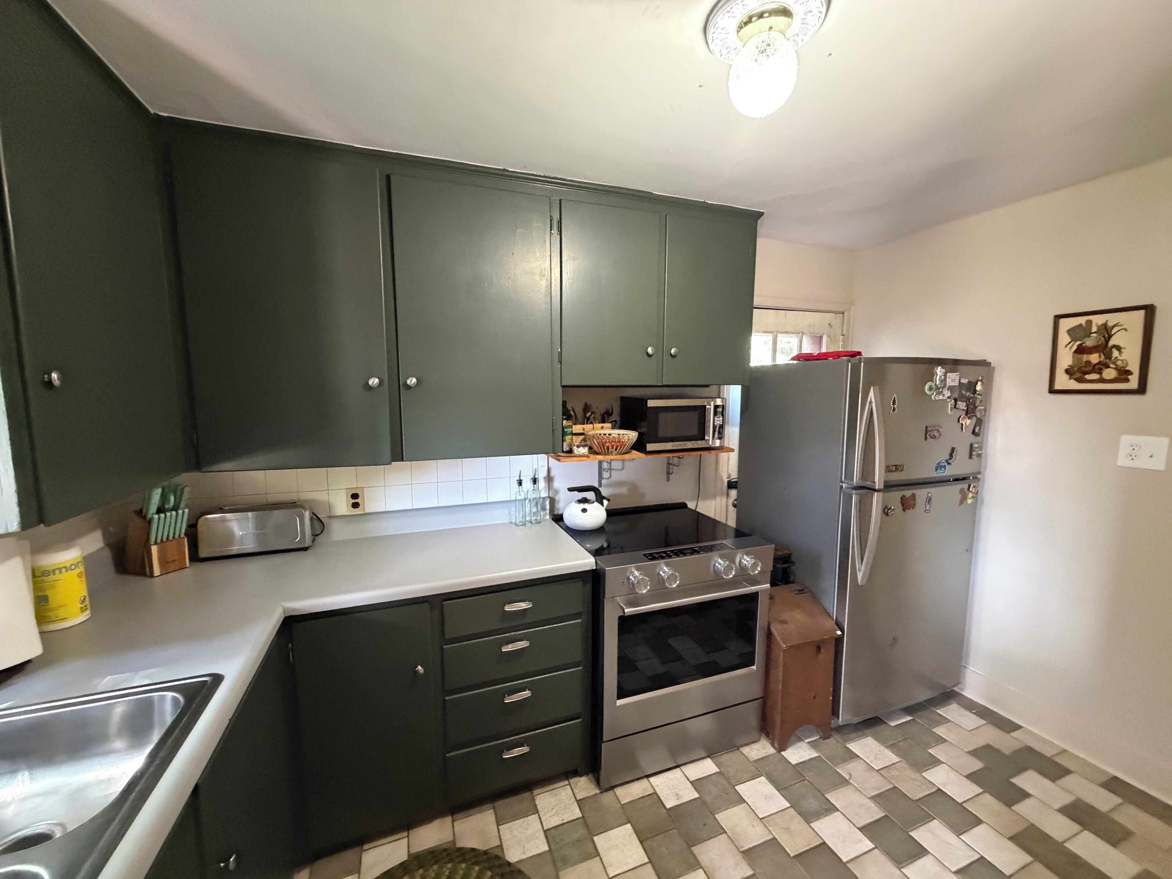 A kitchen with dark cabinets, a microwave, a refrigerator, and a stove.