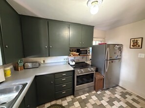 A kitchen with dark cabinets, a microwave, a refrigerator, and a stove. - Charming 3-bedroom house in State College (State College)