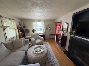 A living room with a sofa, armchair, ottoman, and a fireplace.