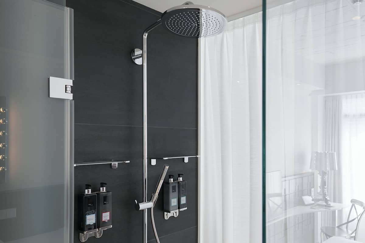 Un baño moderno con ducha, separador de vidrio y vista a un paisaje urbano.