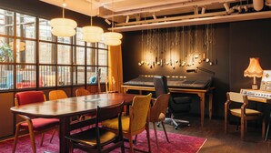 A recording studio with a large mixing console, chairs, a table, and hanging cables. - Ruby Frida Hotel Stockholm By IHG (Stockholm)