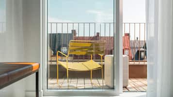 A yellow chair on a balcony with a view of buildings.