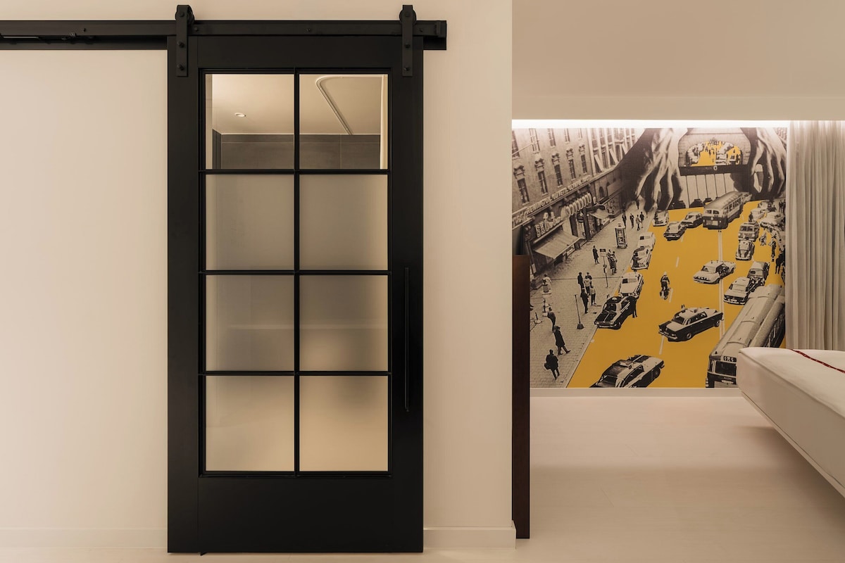 Una habitación con puerta corredera, una cama y un mural de un paisaje urbano.
